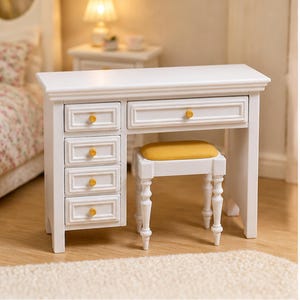 May include: A white miniature vanity desk featuring four stacked drawers on the left side and one wide drawer across the top, each with a small yellow knob. A matching white stool with a yellow upholstered seat is tucked underneath the desk.