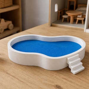 May include: A white, kidney-shaped toy swimming pool with a blue interior surface and a small set of white stairs attached to the side. Two small plastic figures stand on either side of the pool, one wearing a white top and brown shorts, the other in a light-colored top and blue shorts.