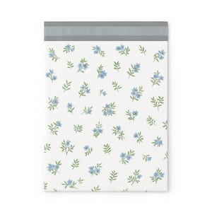 May include: A white padded mailer with a floral pattern of small blue flowers and green leaves. The top edge has a gray band. The design is repeated across the surface of the mailer.