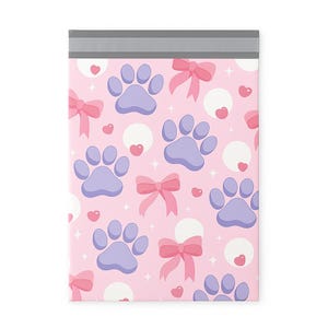 May include: A pink poly mailer with a repeating pattern of light purple paw prints, pink bows, white circles, and small pink hearts. The top edge has a gray strip for sealing.