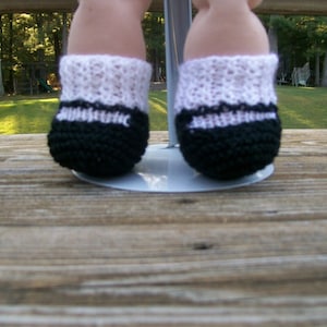 May include: A pair of black and white crocheted baby booties with a white lace trim.