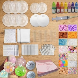 May include: A DIY squeeze toy set including clear and white spherical molds, various colored liquid dyes, a syringe, small plastic bags, gloves, and an assortment of colorful decorative beads and sprinkles, with a box labeled DIY SQUEEZE TOY SET.