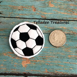 May include: A white and black soccer ball patch with a white border. The patch is about the size of a US quarter.