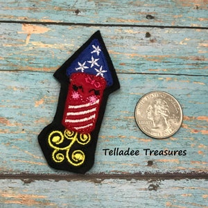 May include: Red, white, and blue embroidered firework patch with a black background and gold trim. The patch is about the size of a quarter. "Telladee Treasures" is written below the patch.