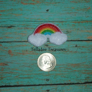May include: A rainbow felt applique with white clouds. The rainbow is made of red, orange, yellow, green, blue, indigo, and violet felt. The applique is about the size of a US quarter.