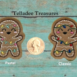 May include: Two felt gingerbread people ornaments with smiling faces and string lights. The gingerbread person on the left has pastel colored lights and the gingerbread person on the right has classic colored lights. The ornaments are about the size of a US quarter.