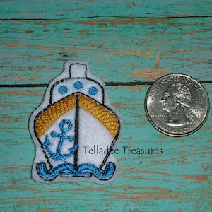May include: A white and blue embroidered patch of a ship with a yellow stripe and an anchor. The patch is about the size of a US quarter.