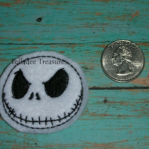 May include: White felt applique of Jack Skellington's face from The Nightmare Before Christmas. The applique is about the size of a US quarter.