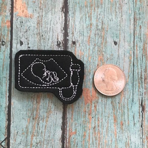 May include: Black felt patch with white embroidery of an ultrasound image of a baby and a medical device. The patch is about the size of a quarter.