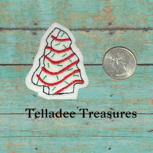 May include: White felt Christmas tree applique with red and green embroidery. The tree is about the size of a US quarter.