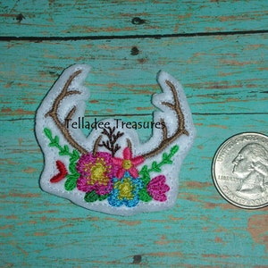 May include: White felt applique with brown embroidered antlers and colorful floral accents. "Telladee Treasures" is embroidered on the applique.