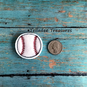 May include: White felt baseball applique with red stitching, next to a US quarter for size comparison. Telladee Treasures is written above the baseball.