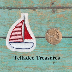 May include: A red and white sailboat applique with blue stitching. The applique is about the size of a US quarter.