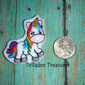 May include: A white felt unicorn applique with a rainbow mane and tail. The unicorn is about the size of a US quarter.