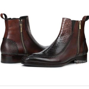 May include: A pair of brown leather ankle boots featuring a textured snakeskin-patterned panel on the side and heel, a side zip closure with a gold-tone pull, a pull tab at the back, and a low stacked heel. The text Imperial Leather Hub is visible.