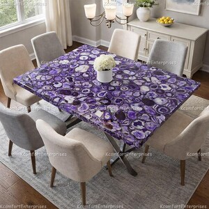 May include: A dining table with a striking purple and white agate stone top, surrounded by six upholstered chairs. The table's surface is a mosaic of natural stone patterns. A vase of white flowers sits on the table. The table has a metal base.