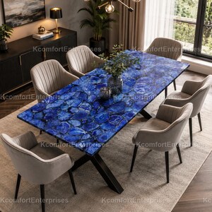 May include: A dining table with a striking blue stone top, approximately 200 cm long, set on a black metal base. Six gray chairs surround the table. The room has a neutral colour scheme, with a rug and a dark wood cabinet.