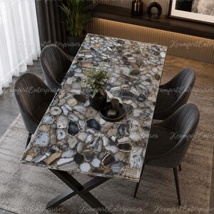 May include: A rectangular dining table featuring a tabletop composed of multi-coloured agate stone slices in shades of grey, brown, and white, supported by a black metal X-shaped base, accompanied by four dark grey upholstered dining chairs.