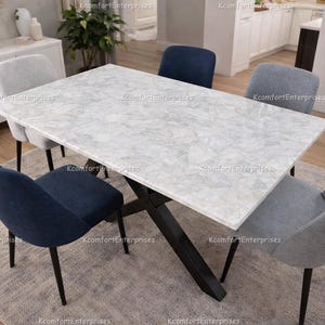 May include: A rectangular dining table with a white marble-effect top and a black metal base. Six upholstered chairs in shades of blue and grey surround the table. The table is approximately 183 cm long.