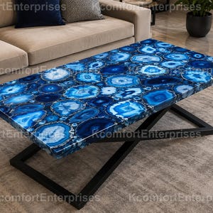 May include: A rectangular coffee table featuring a tabletop composed of numerous blue agate slices with varied concentric patterns and shades of blue, supported by a black metal base with a crisscross design and a flat, rectangular frame.