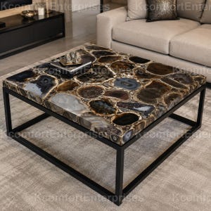 May include: A square coffee table featuring a tabletop composed of polished, multi-colored agate slices in shades of brown, gray, and black. The table is supported by a simple, thin black metal frame with a square base and four vertical legs.