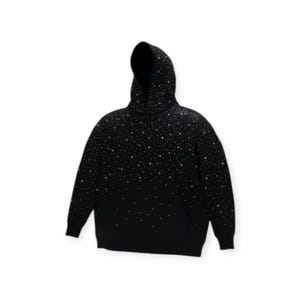 Pode incluir: Moletom preto com capuz com um padrão de pontos brancos, criando um efeito de céu estrelado. O moletom tem mangas compridas e um capuz. O design é gradiente, com mais pontos na parte superior e menos na inferior.