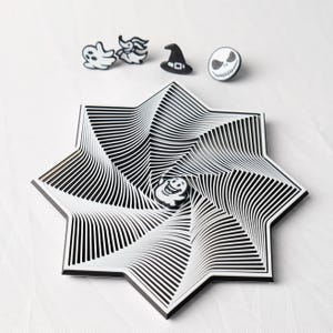 May include: A black and white star-shaped decorative tray with a swirling design. The tray has a black border and a small, round, smiling ghost pin in the center. Above the tray are four pins: a ghost, a bat, a witch hat, and a Jack Skellington face.