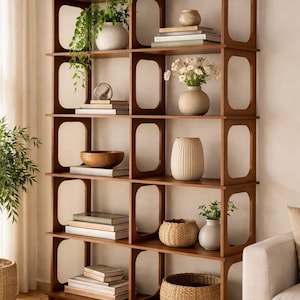 Puede incluir: Una estantería de madera con múltiples estantes, cada uno con objetos decorativos. Los estantes exhiben plantas en jarrones, libros y cestas tejidas. La estantería es de color marrón cálido y tiene un diseño moderno.