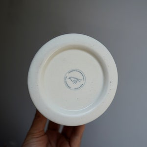 Pu&ograve; includere: Tazza in ceramica bianca con un logo di uccello bianco e nero che recita "Microwave & Dishwasher Safe. Made in China. Crafted for the Home."