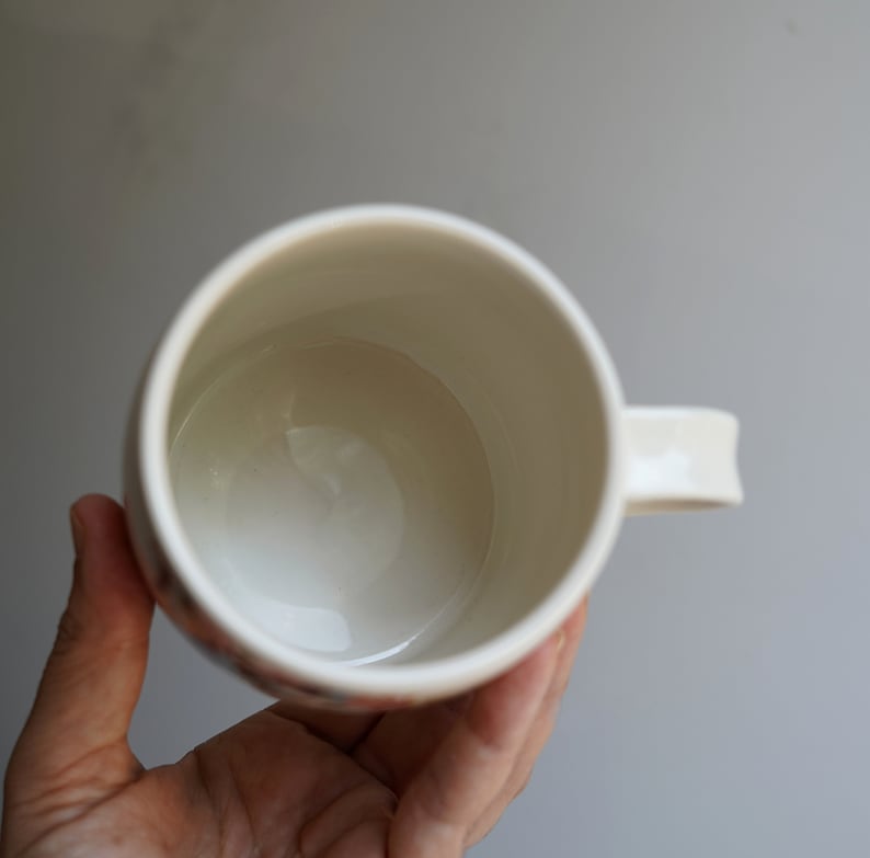 Pu&ograve; includere: Una tazza in ceramica bianca con un manico. La tazza &egrave; vuota e l'interno &egrave; visibile.