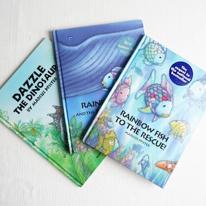 May include: Three children's books are displayed, featuring colorful illustrations and titles. The books include "Dazzle the Dinosaur," "Rainbow and the...", and "Rainbow Fish to the Rescue!" by Marcus Pfister. The covers showcase vibrant artwork of dinosaurs and fish.