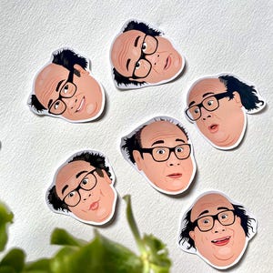 May include: Five die-cut stickers with a cartoon illustration of a man's face wearing black-framed glasses. The stickers have a white border and are on a white surface. The man has dark hair and a light skin tone.
