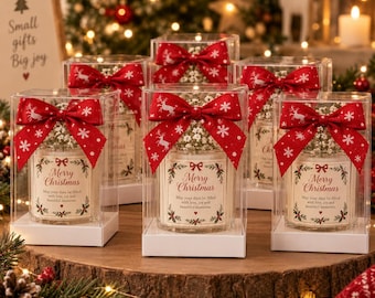 May include: A set of clear square boxes containing candles with white baby's breath flowers. Each box features a red ribbon with white reindeer and snowflake patterns. The candle labels read Merry Christmas with festive holly illustrations.