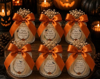 May include: Six glass candles with ribbed sides, each topped with dried baby's breath and a burnt orange satin bow. Each candle features a circular label with Halloween-themed text, family names, and the year 2026, plus a cardboard thank you tag.