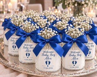 May include: A collection of glass jars filled with white baby's breath flowers, each tied with a blue satin ribbon. The labels feature the text Welcome Baby Boy Alex, a pair of blue footprints, and the date 12.06.2026 printed in blue ink.