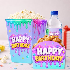 Op de afbeelding: Een popcornbak en een snackdoos, beide met een lichtblauw en paars verloop met een druipend slijmontwerp, kleurrijke sterren en de tekst "HAPPY BIRTHDAY" in wit en geel. Een doorzichtige waterfles met een blauwe dop is inbegrepen.