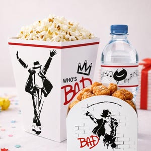 Pode incluir: Um balde de pipoca branco com a silhueta preta de um dançarino e o texto vermelho WHO'S BAD, uma garrafa de água de plástico transparente com tampa azul e rótulo de notas musicais, e um recipiente branco menor com pedaços de frango frito.