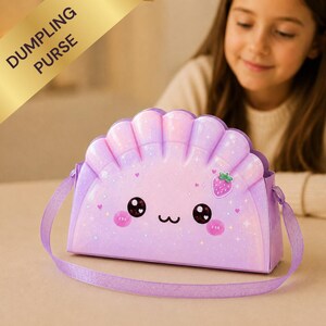 May include: A light purple, semi-circular dumpling-shaped purse with a glossy, iridescent finish. The front features a printed kawaii face with large black eyes, pink cheeks, and a small strawberry icon. It includes a matching purple shoulder strap.