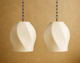 May include: Two off-white pendant lights with a spiral design hang from black chains. The lights have a rounded shape and are suspended against a neutral background, suggesting a modern home decor theme.