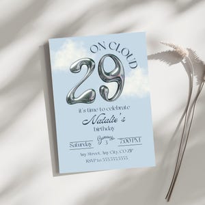 May include: A light blue birthday invitation with the text "ON CLOUD 29" in silver metallic lettering. The invitation reads "it's time to celebrate Natalie's birthday" with the date, time, and RSVP information.
