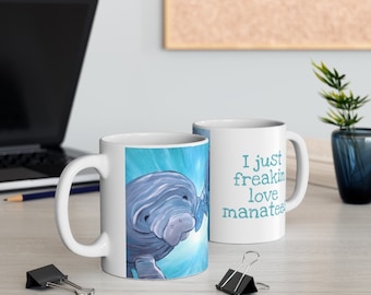 May include: White ceramic mug with a blue and white illustration of a manatee swimming in the ocean. The text "I just freakin love manatees" is printed on the mug.
