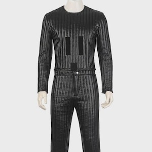 Puede incluir: Disfraz negro con rayas verticales, con mangas largas y pantalón a juego. La parte superior presenta dos rectángulos negros verticales y un rectángulo horizontal. El atuendo se muestra en un maniquí.