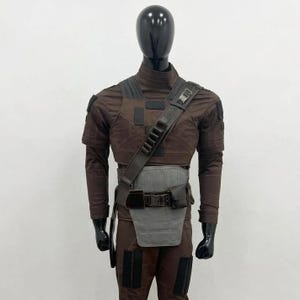 May include: A dark brown tactical costume set featuring a long-sleeved top and trousers with black rectangular patches. The outfit includes a dark brown shoulder strap with ammunition loops and a light grey waist guard with a black utility belt.