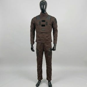 May include: A dark brown tactical uniform set consisting of a long-sleeved shirt with a high collar and matching trousers. The shirt features black rectangular patches on the chest and shoulders, while the trousers include black knee panels.