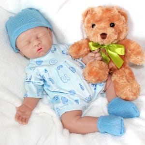 A baby doll holding a pacifier, next to a plush stuffed animal, set against a pastel background.