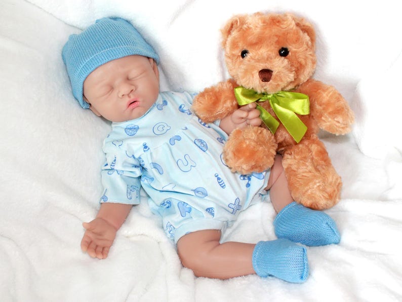 A baby doll holding a pacifier, next to a plush stuffed animal, set against a pastel background.