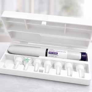 Puede incluir: Un estuche de almacenamiento de plástico blanco que contiene una pluma precargada multidosis gris con una tapa morada y siete puntas de aguja blancas. La etiqueta dice: For Single Patient Use only, Once weekly, 1 multiple-dose pre-filled pen.