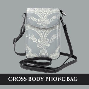 May include: A gray cross body phone bag with a white floral pattern. The bag has a black strap and the text "CROSS BODY PHONE BAG" at the bottom.