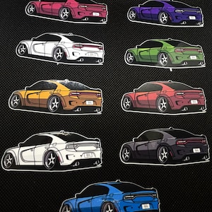 May include: A collection of car stickers in various colors, including pink, purple, white, green, yellow, red, black, and blue. Each sticker features a stylized illustration of a car with custom wheels and a white border.