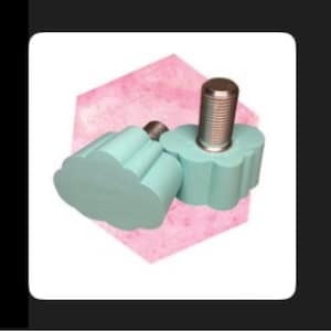 May include: Two light blue roller skate toe stops with a cloud-like shape. The stops have a silver metal threaded post. The background is a pink watercolor hexagon shape on a white background.